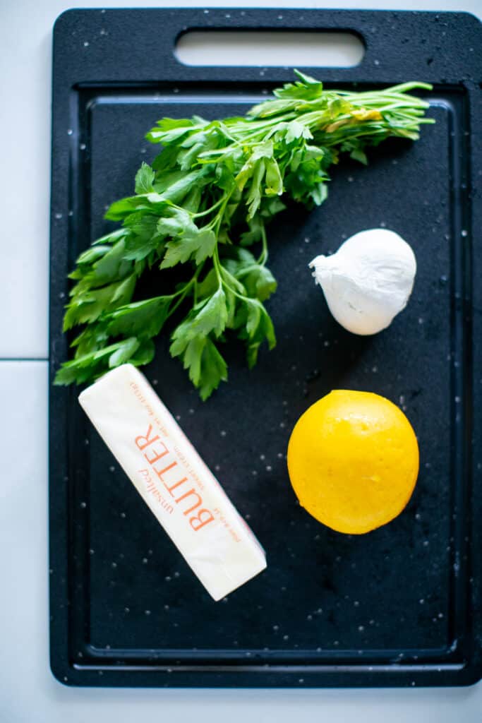 Parsley, lemon, butter and garlic on a cutting board