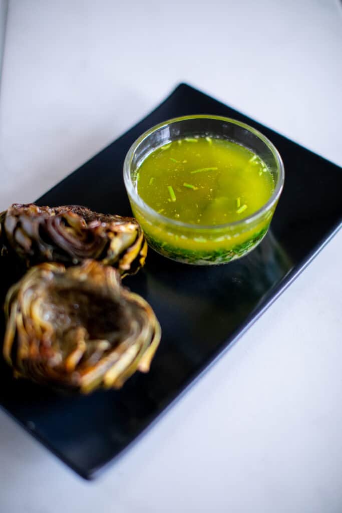 Roasted artichokes on a plate with lemon garlic butter sauce