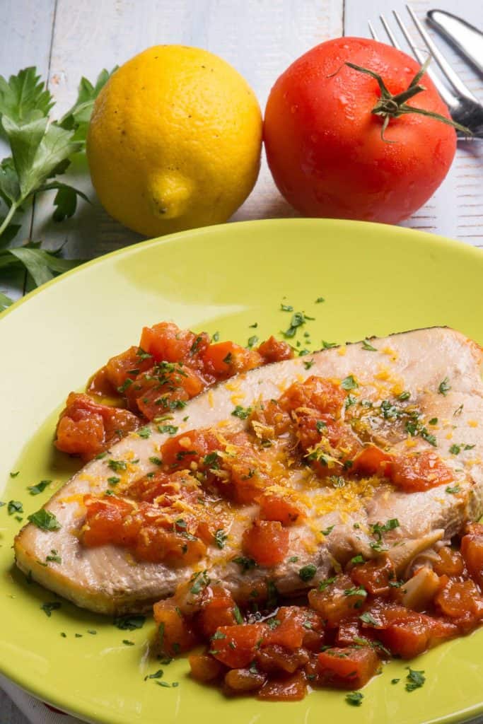 Swordfish with fresh tomatoes and grated lemon peel on a plate