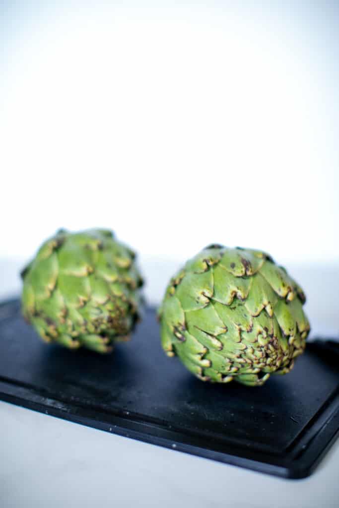 A pair of artichokes on a cutting board