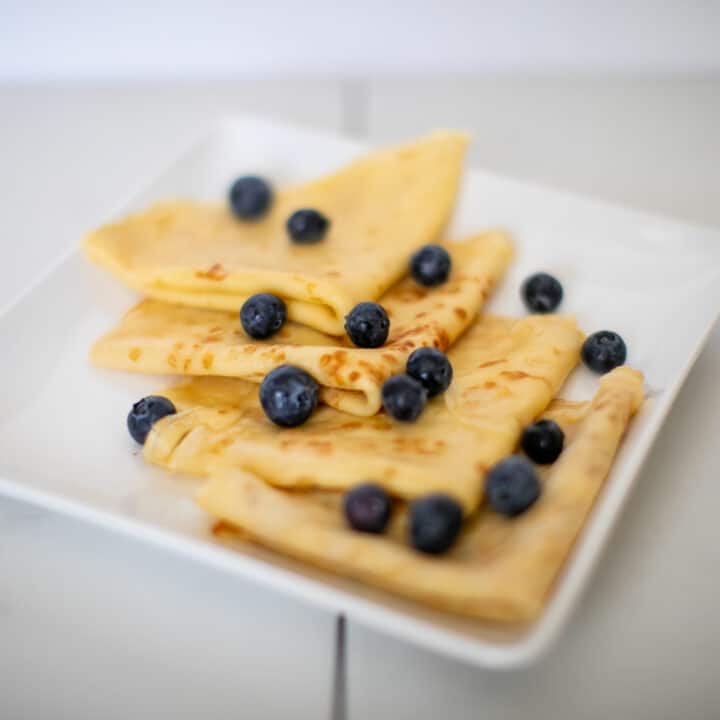Simple french crepes recipe topped with blueberries on a plate
