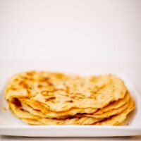 Indian naan bread prepared on a white plate placed on a white surface