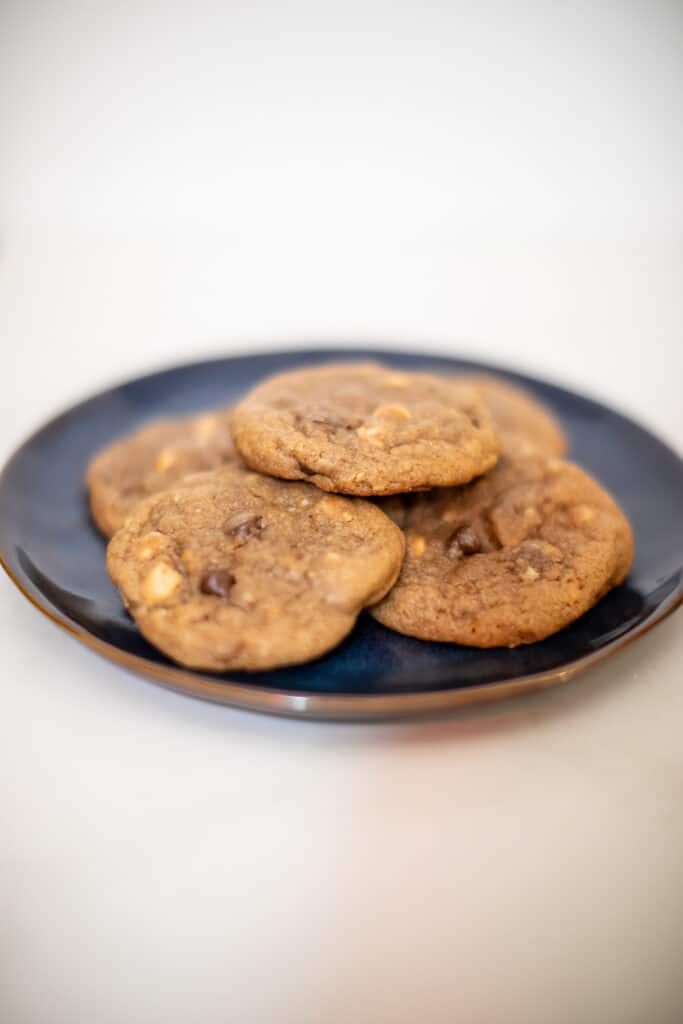 Peanut butter chip cookies served on a black plate placed on a white surface