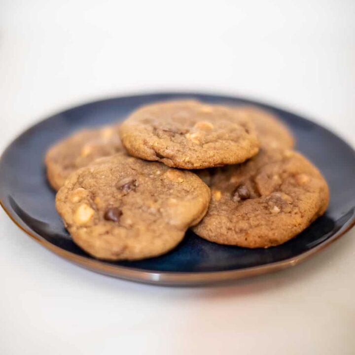 Peanut butter chip cookies served on a black plate placed on a white surface
