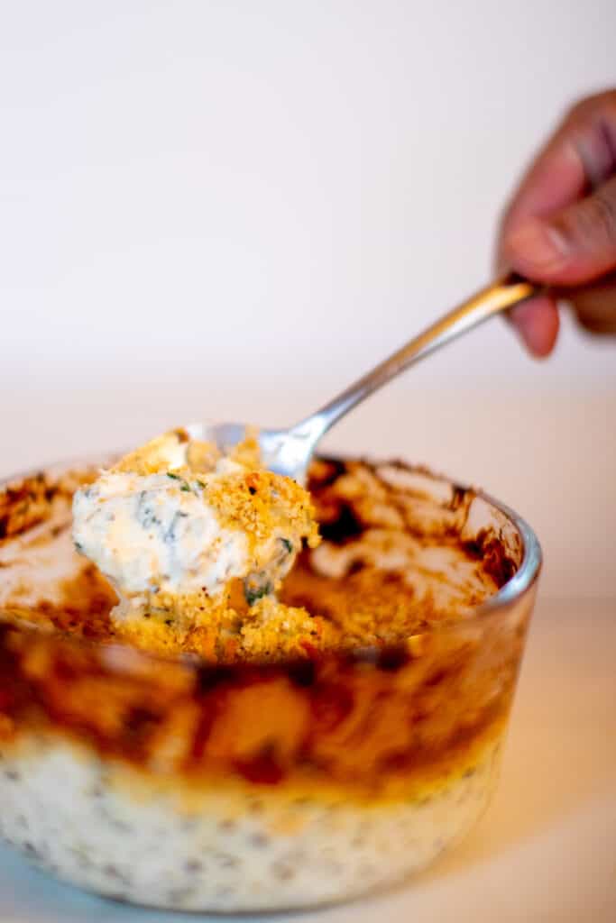 Baked spinach artichoke dip being mixed with a spoon