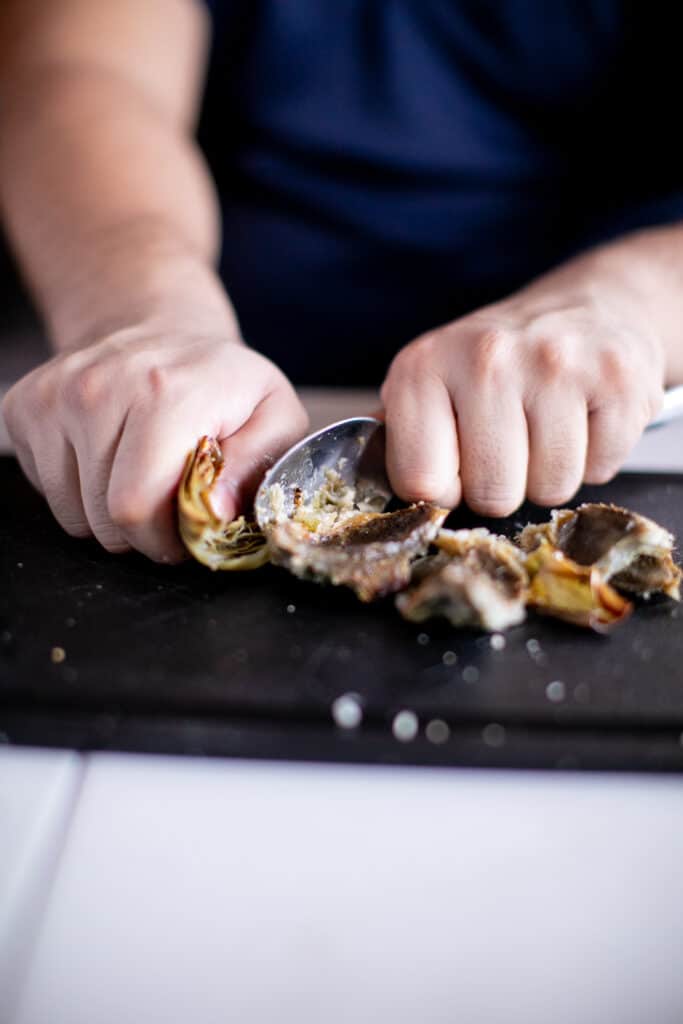 Person cutting up artichokes with a spoon