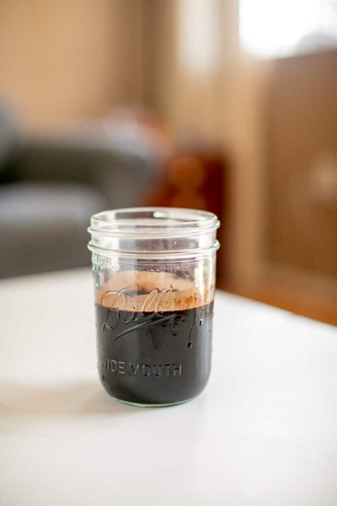 Cocoa powder chocolate sauce in a mason jar placed on a white table