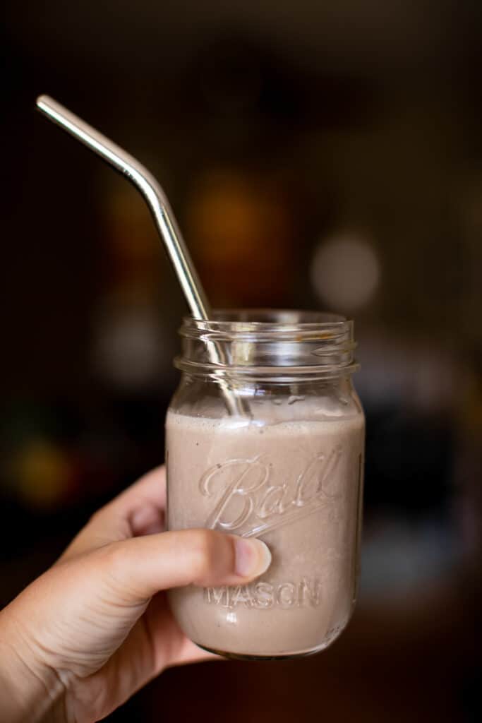 Person holding a mason jar filled with chocolate peanut butter banana smoothie