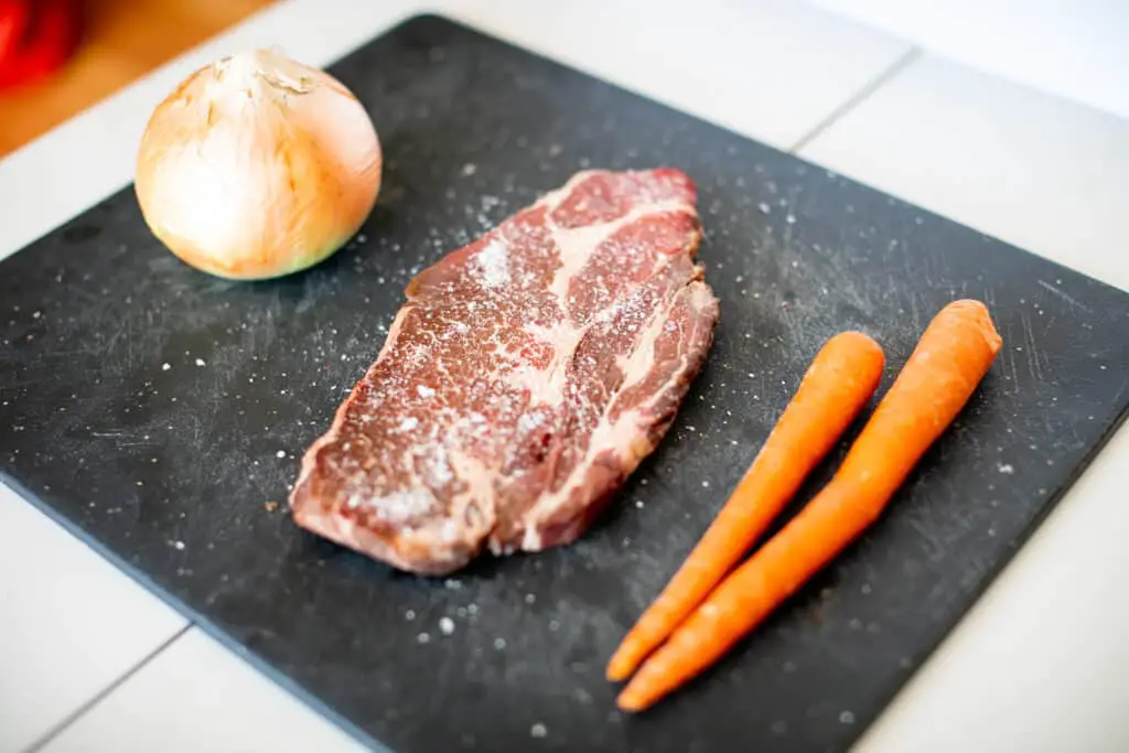Beef chuck, carrots and onion in a cutting board