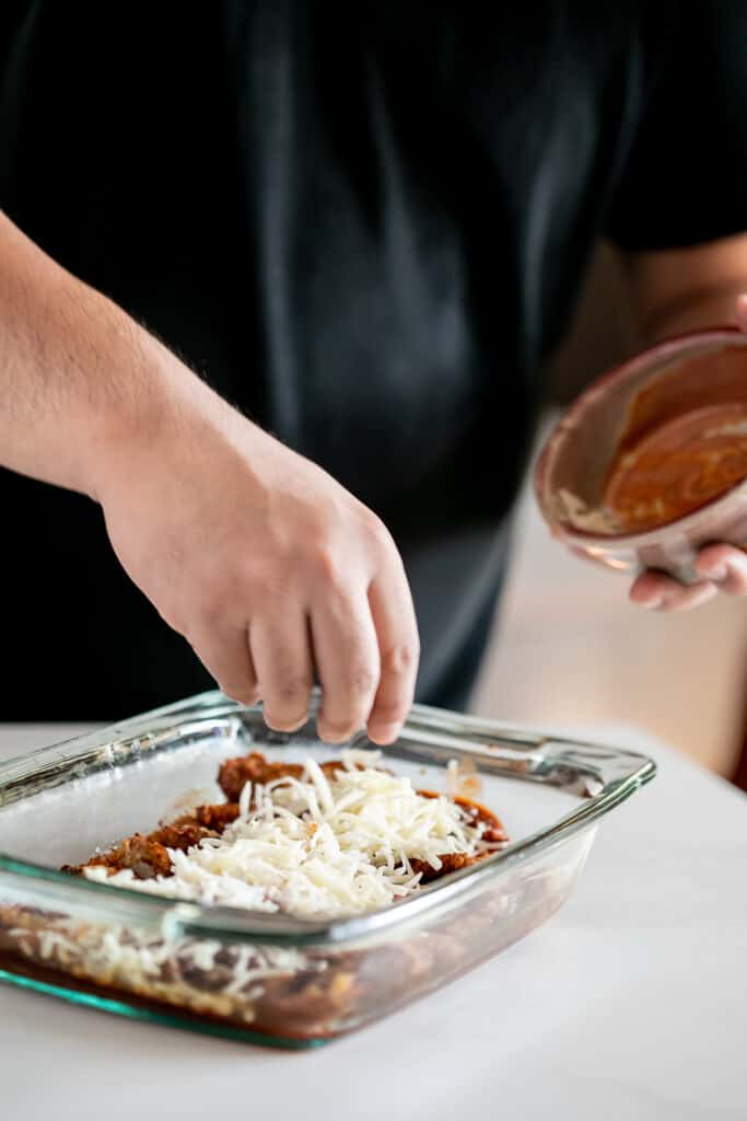 Person putting cheese on top of the breaded veal