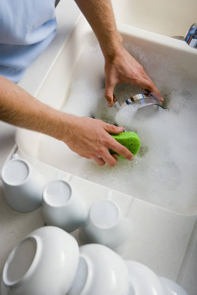 Cleaning meat grinder parts with soap and sponge in the sink