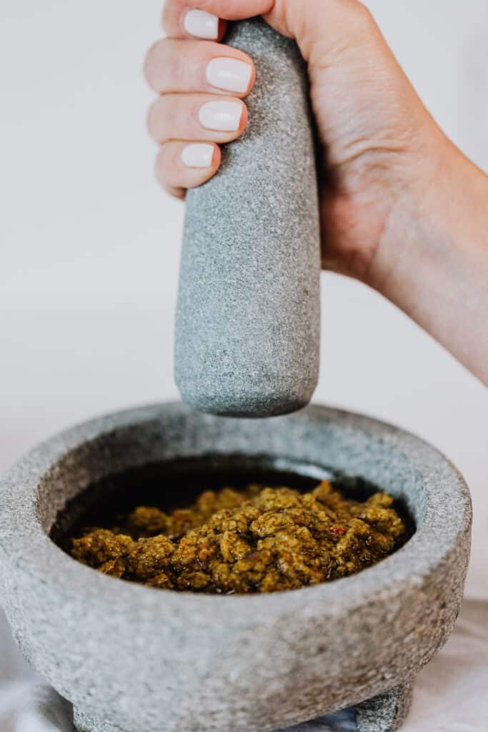 Woman using a mortar and pestle to grind an oil based sauce