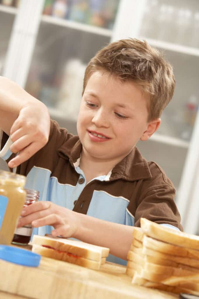 Young boy making a peanut butter and jelly sandwich