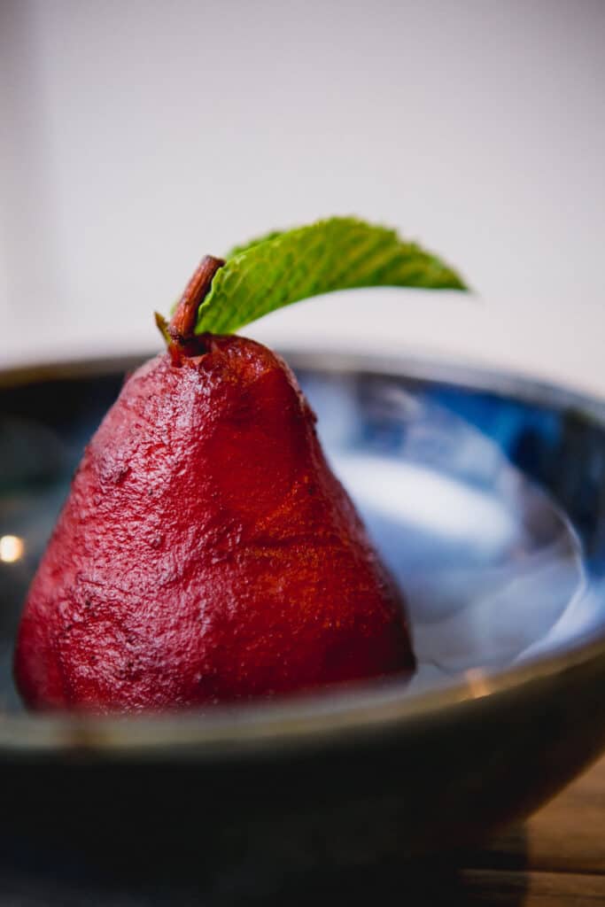 Mulled wine poached pear in a blue bowl