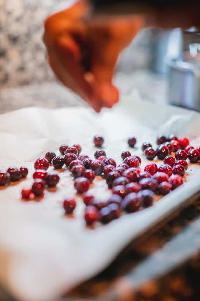 Person dusting sugar on fresh cranberries