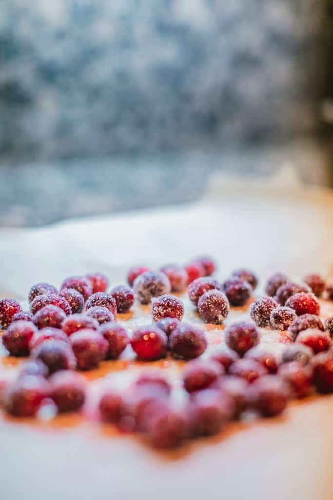 Fresh cranberries topped with powdered sugar placed on parchment paper