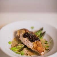 Oven-roasted whole Pheasant with sauce and asparagus served in a white bowl