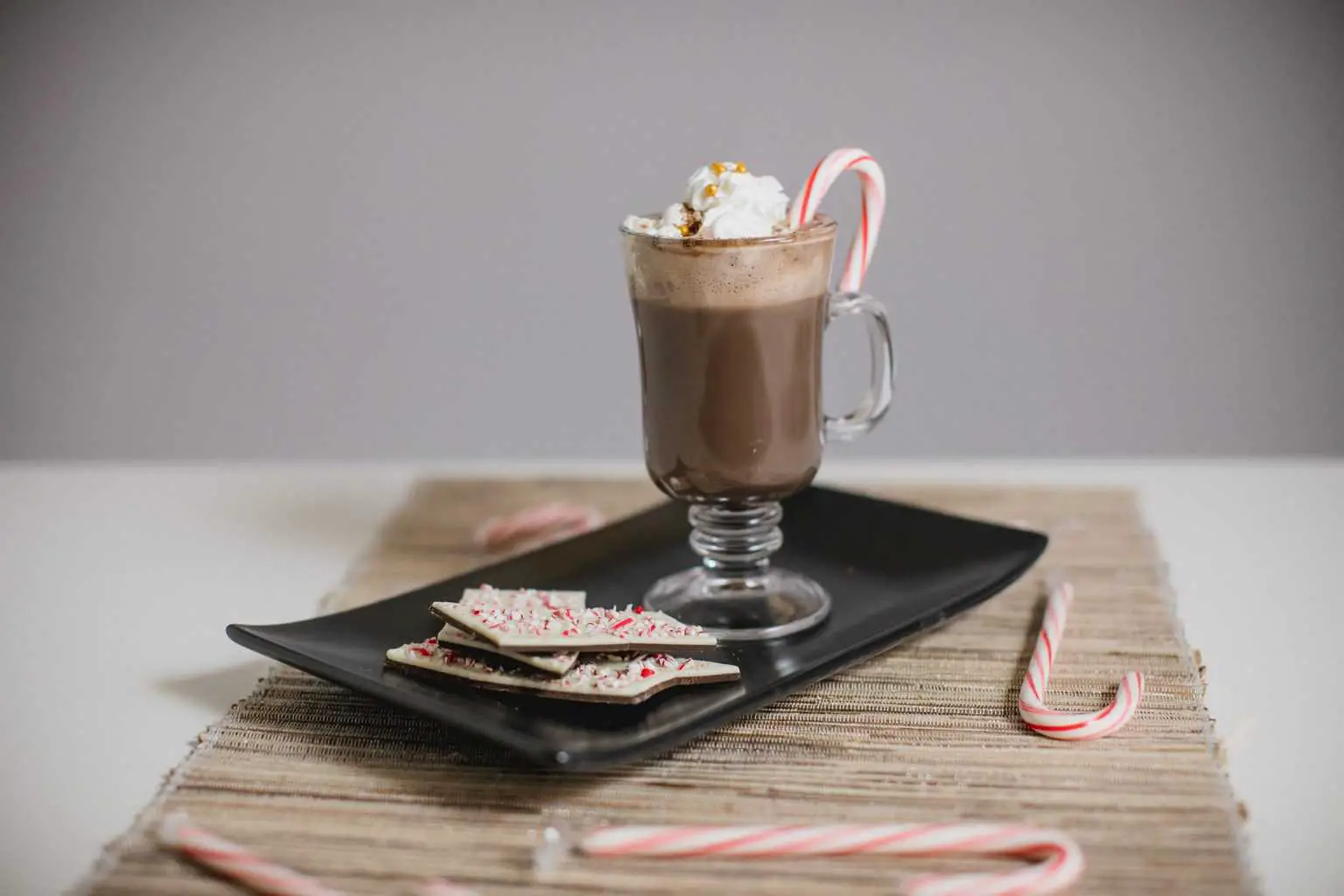 Glass of peppermint hot chocolate recipe with candy canes on the table