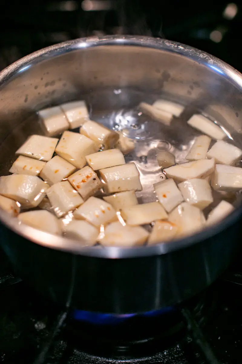 Chopped parsnips boiling in hot water in a pot on the stove.