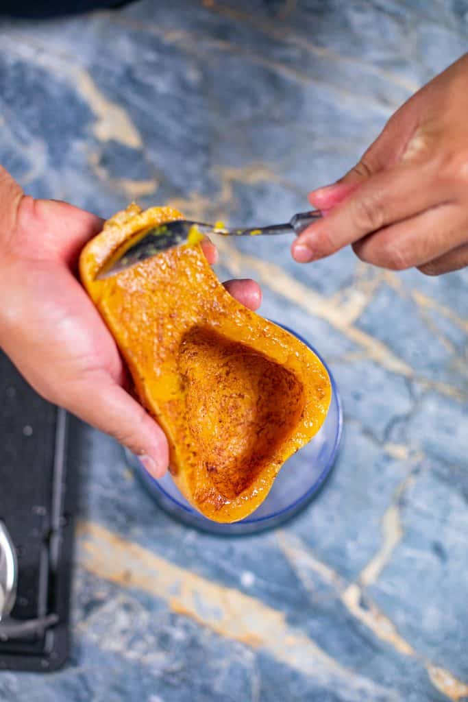 Person removing the meat from a roasted squash