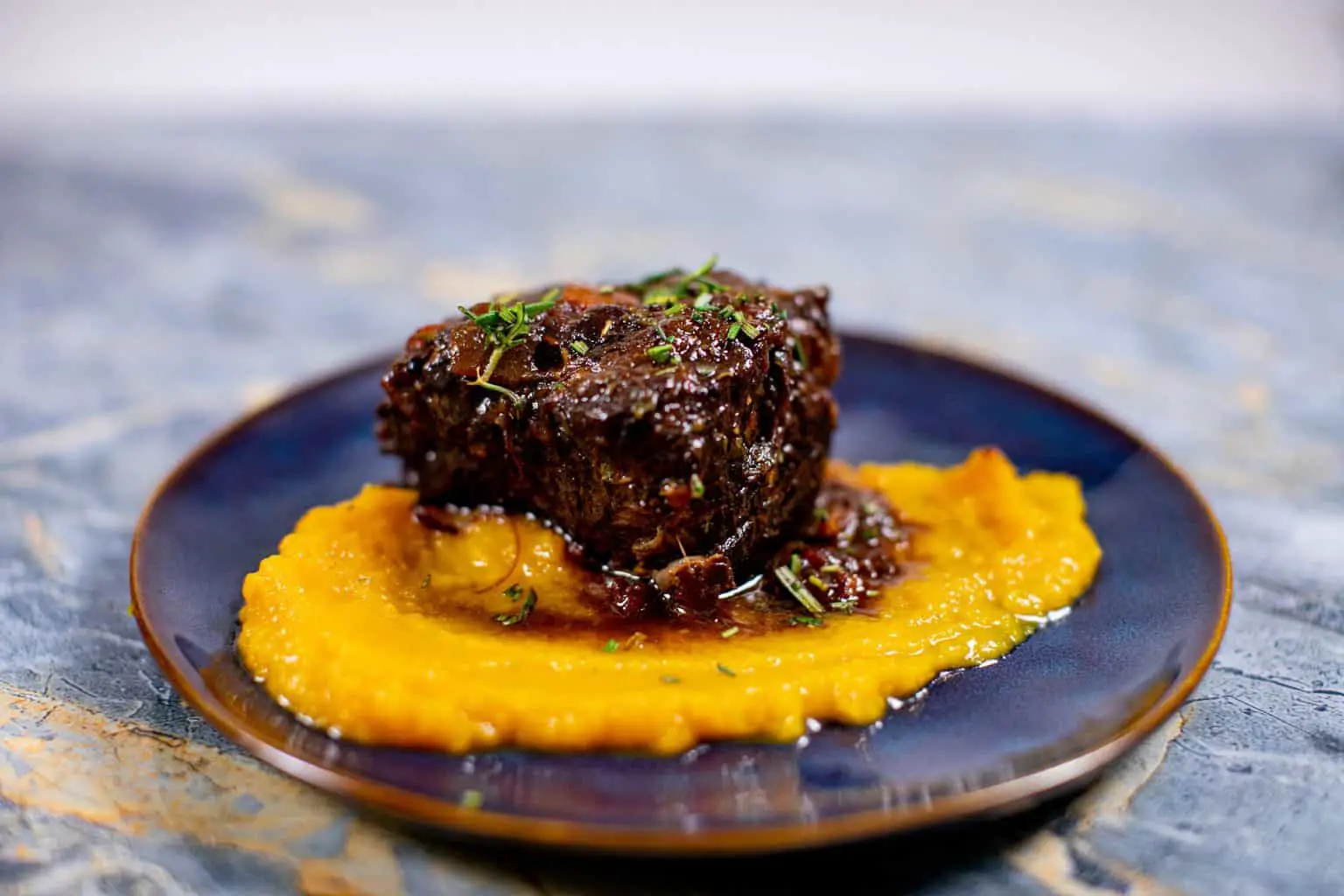 Prepared butternut squash puree recipe with braised meat on a plate