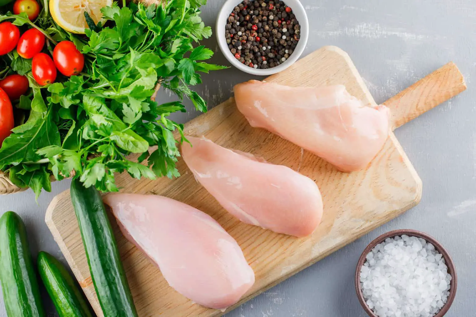 chicken fillet on chopping board with herbs