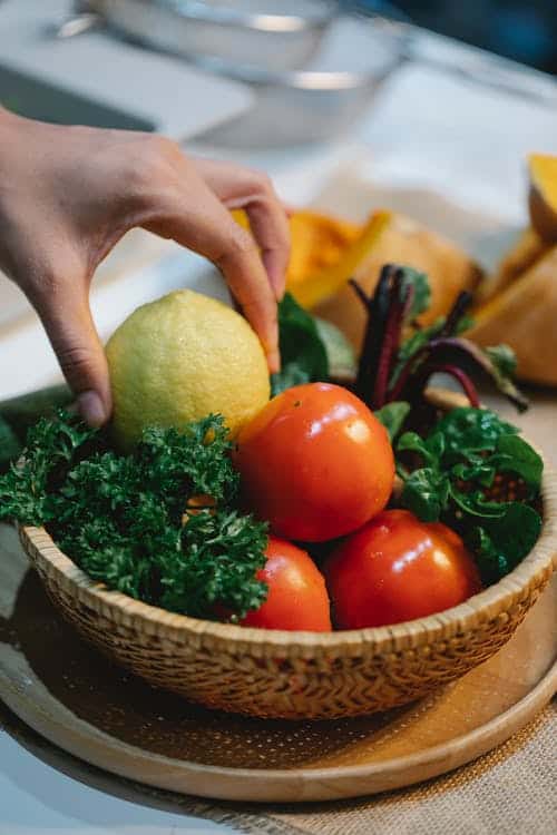 Hand picking out a lemon in a fruit basket