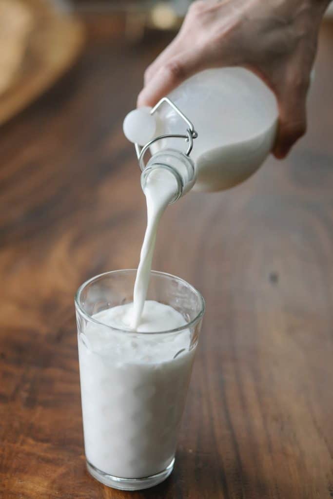 Hand pouring milk into a glass