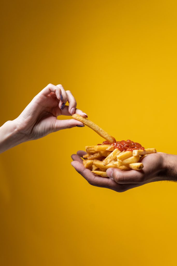 Hand dipping her french fries in ketchup