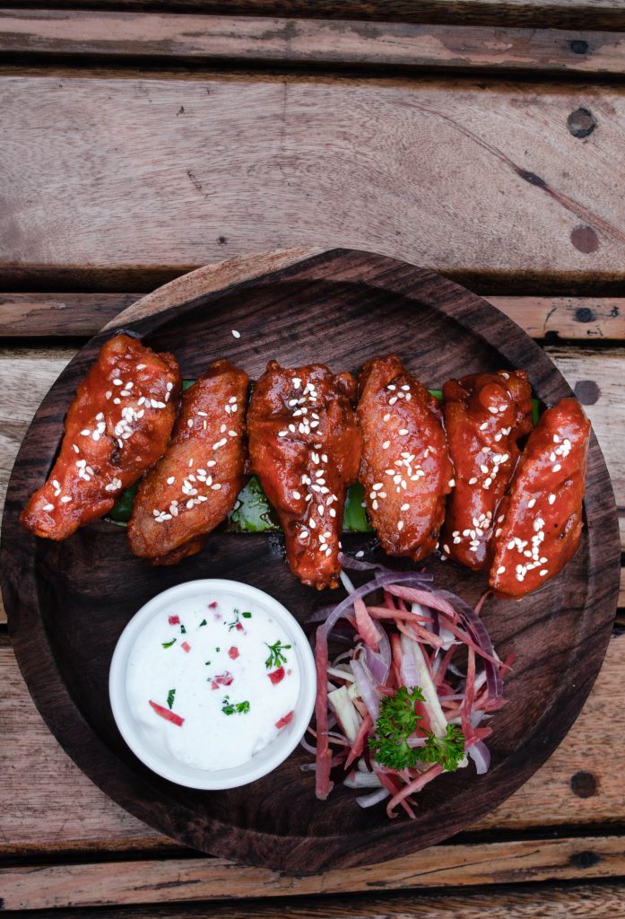 Barbecue flavored chicken wings in line on a circular plate