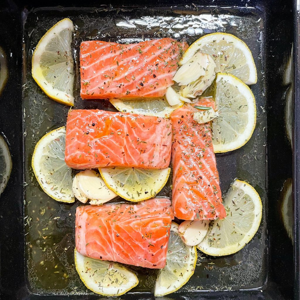 Four pieces of sliced salmons with sliced lemons