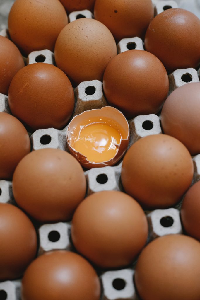 A tray of eggs and an open egg in the middle