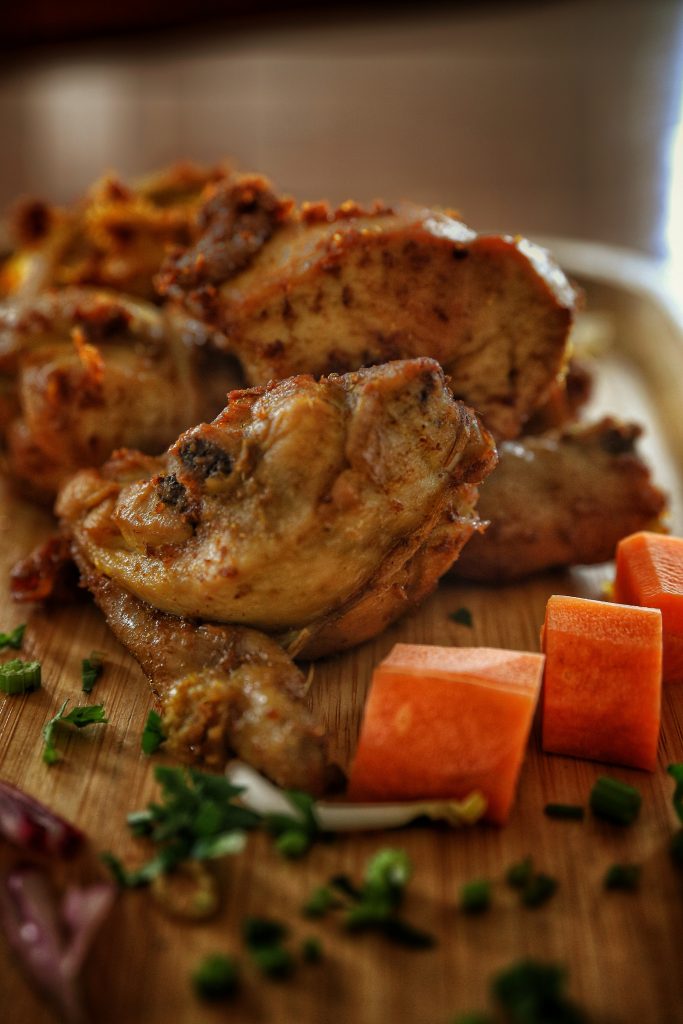 Fried chicken on a chopping board with bits and seasoning