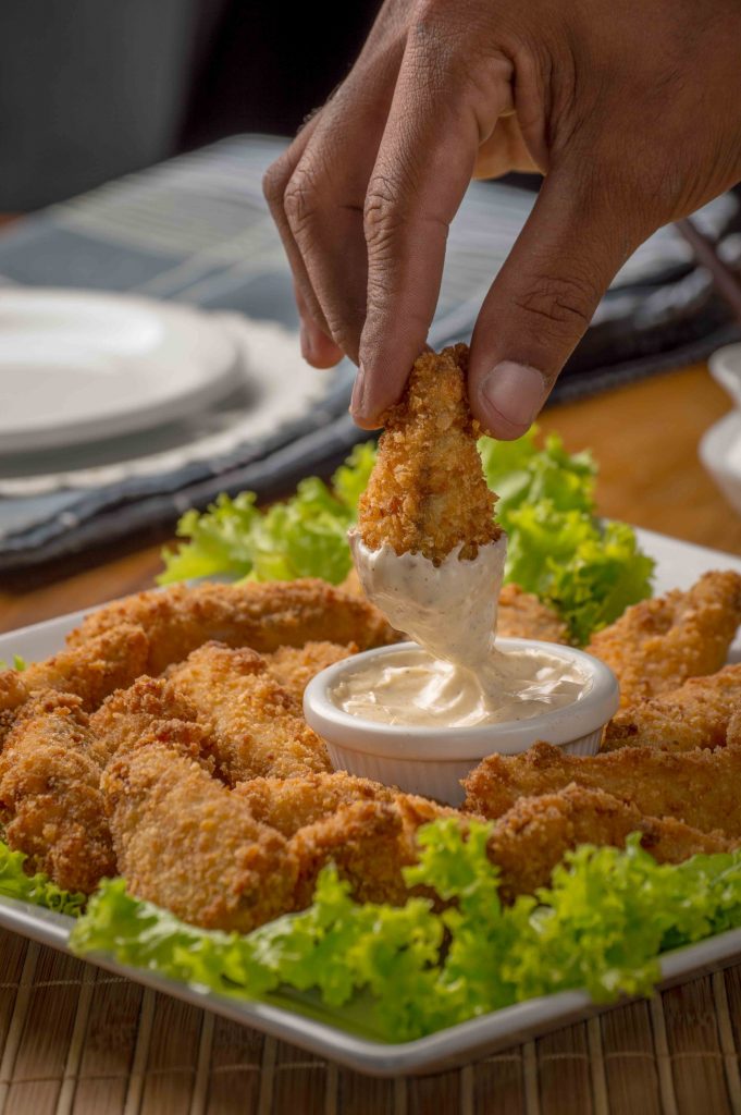 Dunking a fried chicken to the white sauce