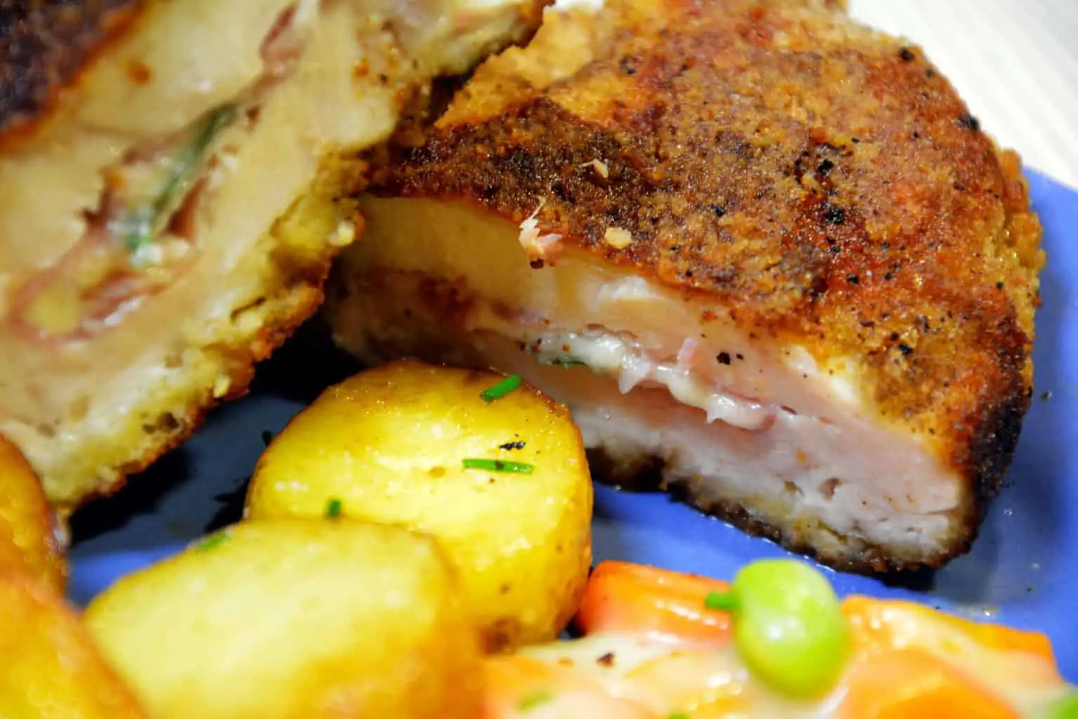 Close up shot of a sliced chicken cordon bleu with side dishes