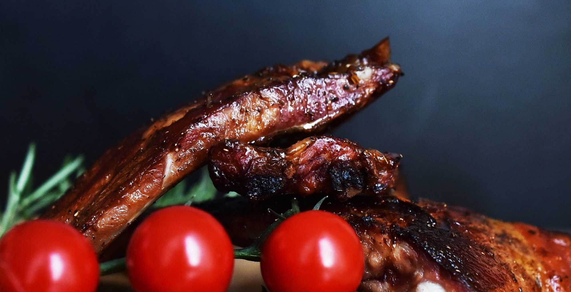 Close up shot of served riblets with tomatoes