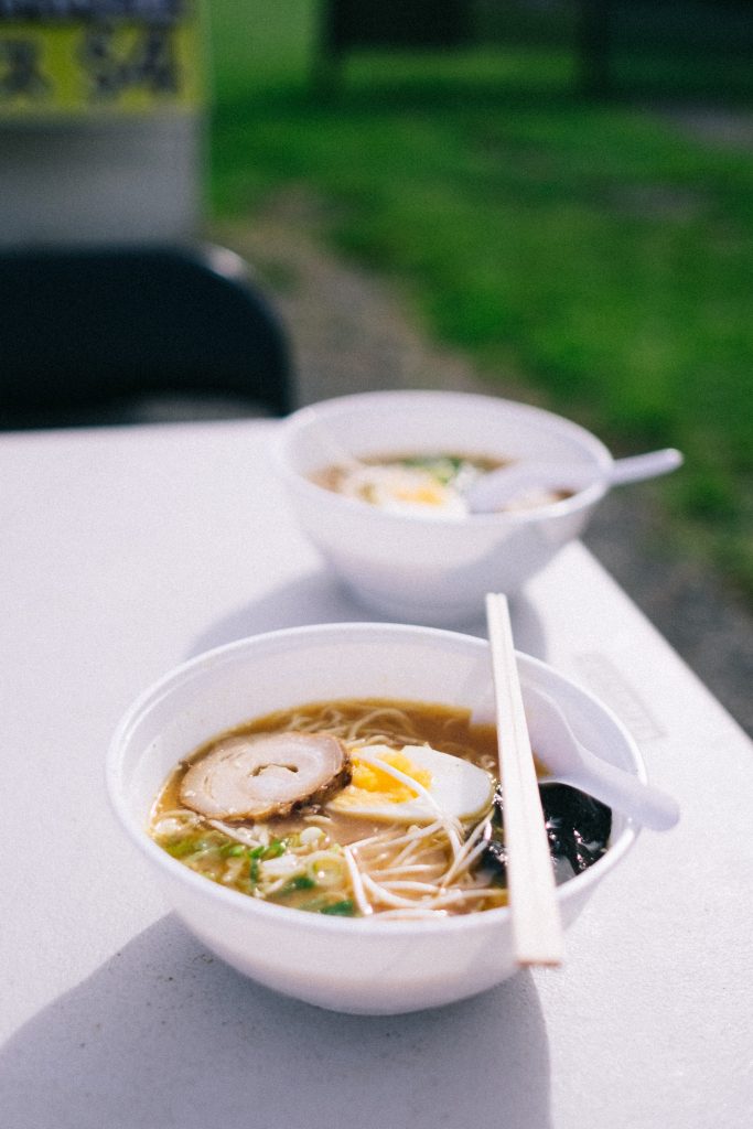 Two noodle soup bowls served outdoors with chopsticks