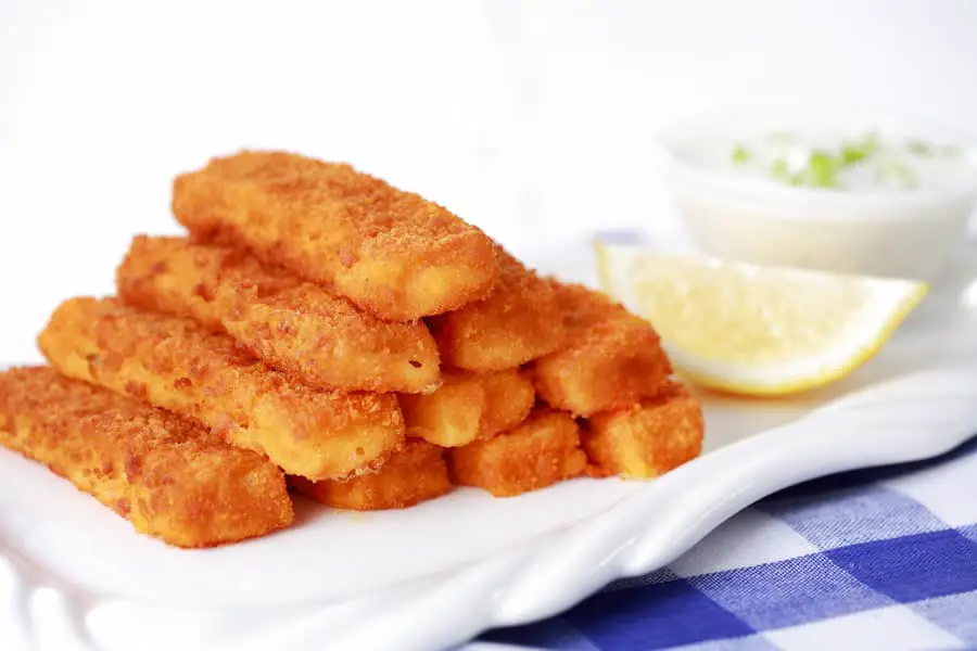 Fish sticks with lemon on a white serving plate