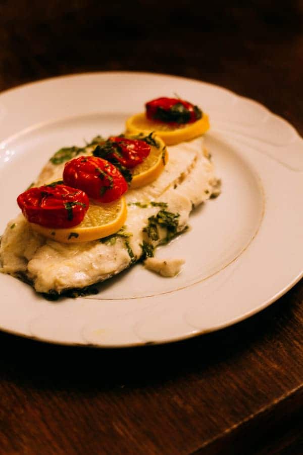 Delicious cod fish with lemon and tomatoes on top