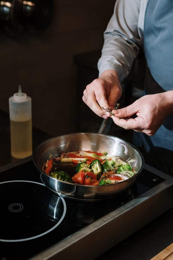 Man cooking vegetables on stainless steel pan