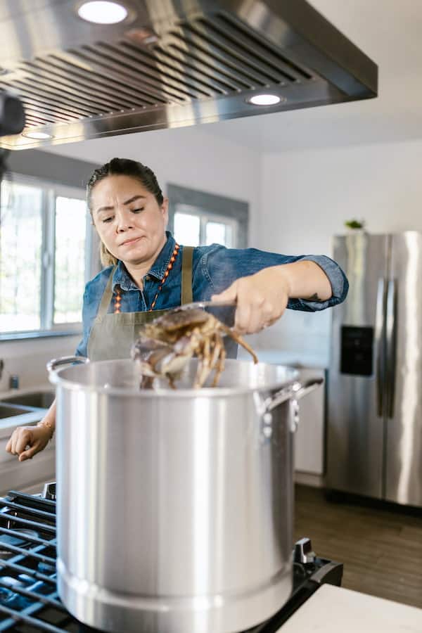 A woman using stock pot for cooking crab