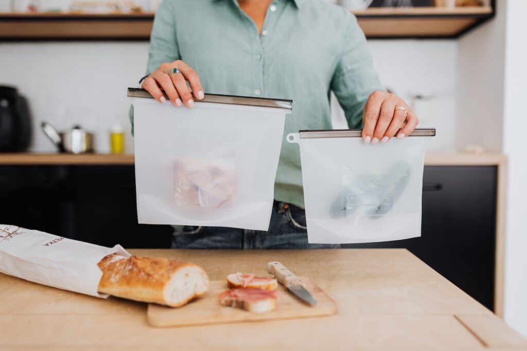 A person wearing green long sleeves holds two plastic containers with food inside