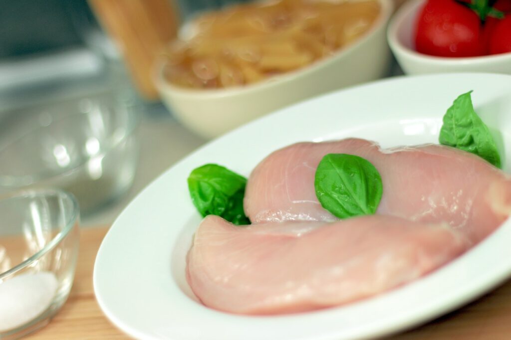 Chicken breasts with herbs on a white plate placed on a brown chopping board