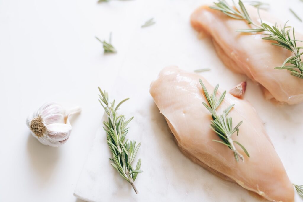 Two-sliced chicken breasts with rosemary herbs toppings placed on a white surface