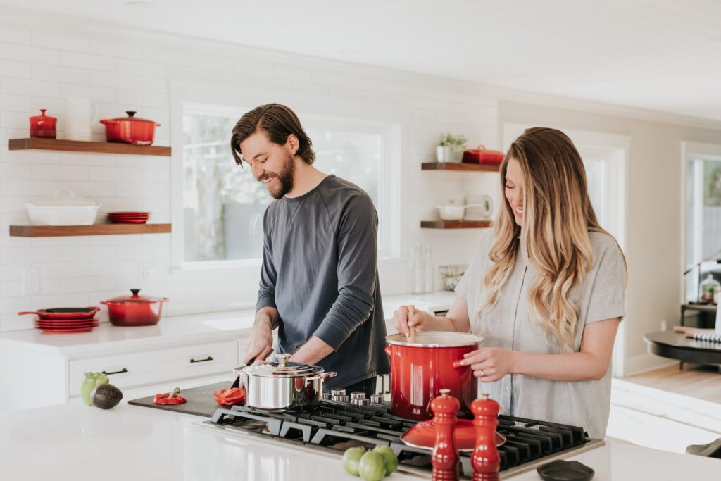 A woman cooking in a red pot while a man chopping the ingredients in the kitchenA woman cooking in a red pot while a man is chopping the ingredients in the kitchen