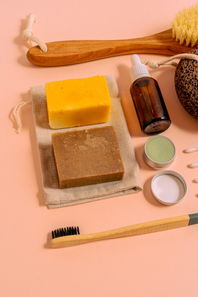 Cleaning products like soap, sponges, and brushes placed on a pink surface