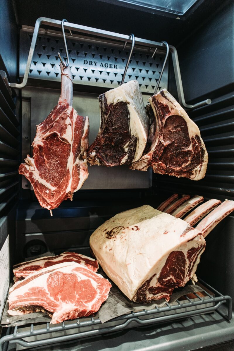 Belted galloway dry aged steaks on a silver hook and silver rack