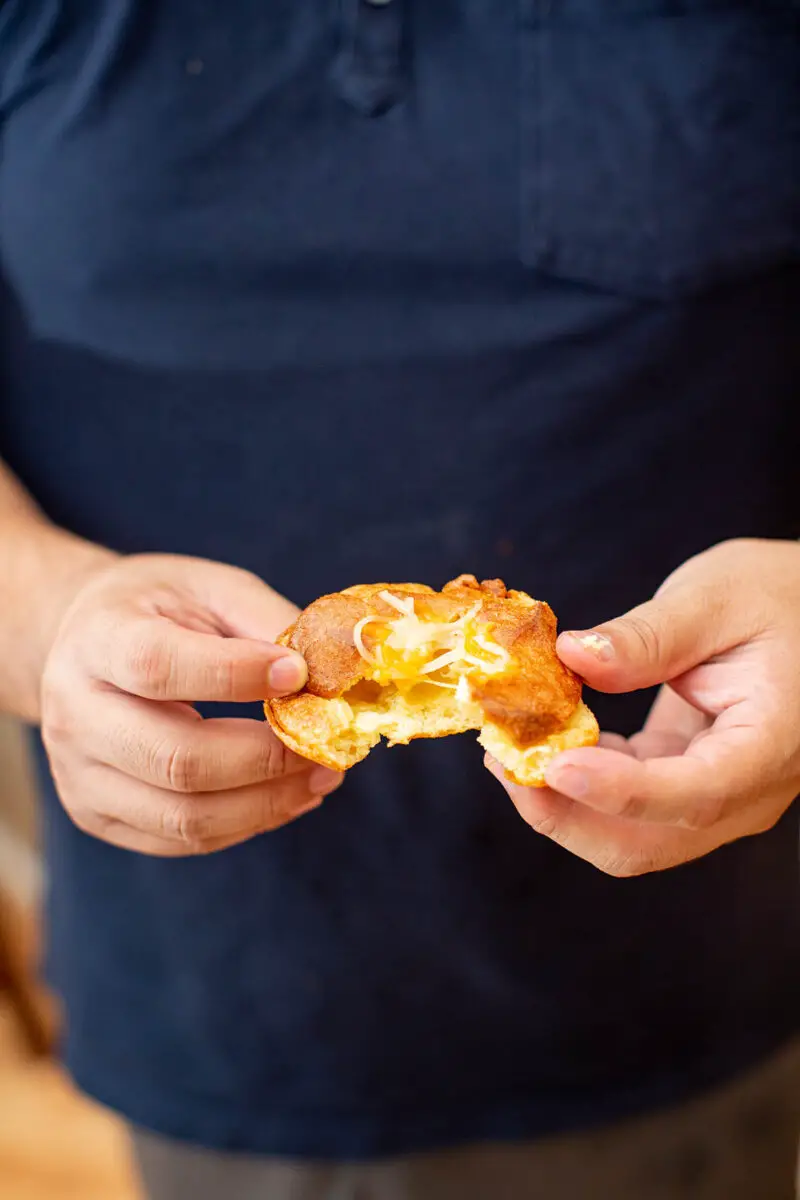 Man pulling apart a popover with his hands to show how light and airy it is on the inside
